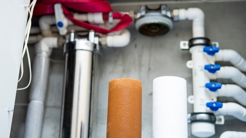 Cartouches de filtration installées sous un évier, dont une au charbon actif